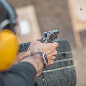 person shooting a target behind a tire